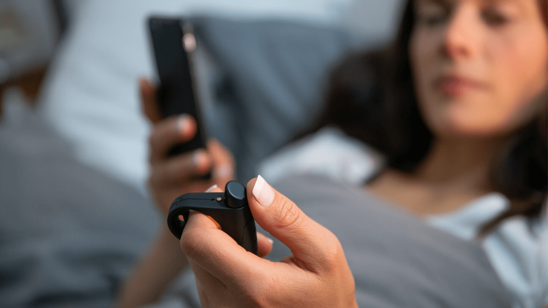 Woman in bed with her phone and SleepCogni sleeping device