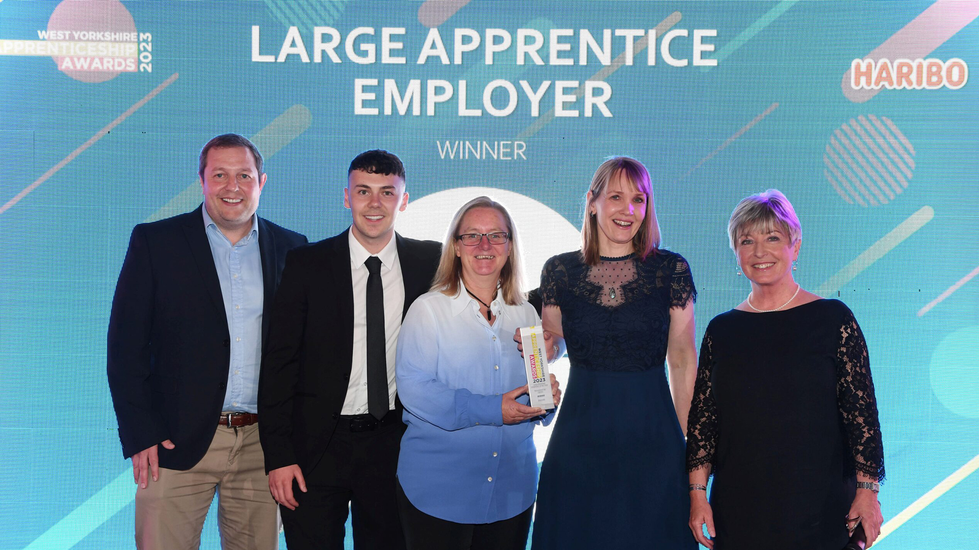 people posing and smiling for a photo holding an award