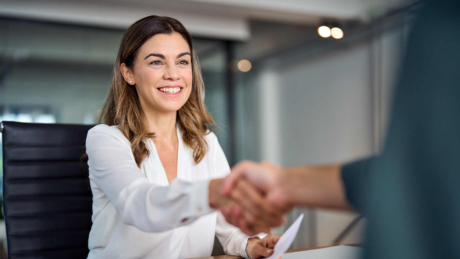 Happy mid aged business woman manager handshaking at office meeting