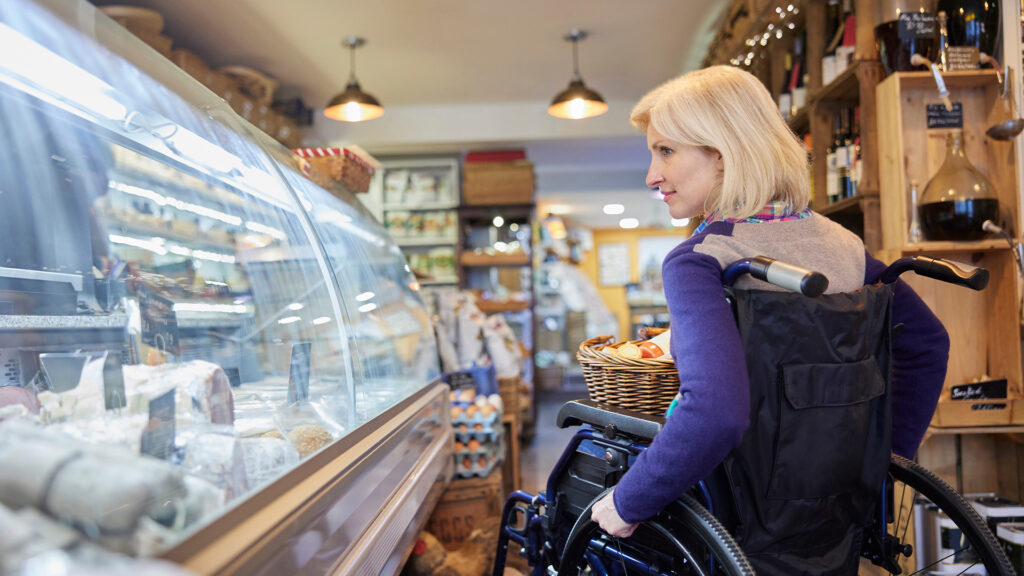 Woman In Wheelchair Shopping For Food In Delicatessen