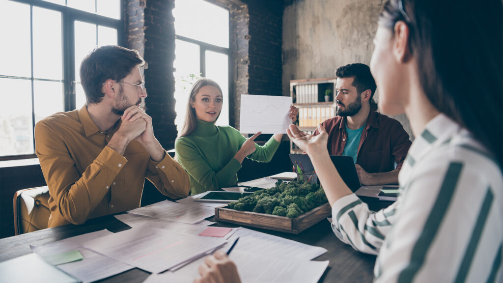 Company of four nice attractive professional skilled people manager agent broker sitting around table desktop discussing terms agreement at industrial loft interior style work place station office