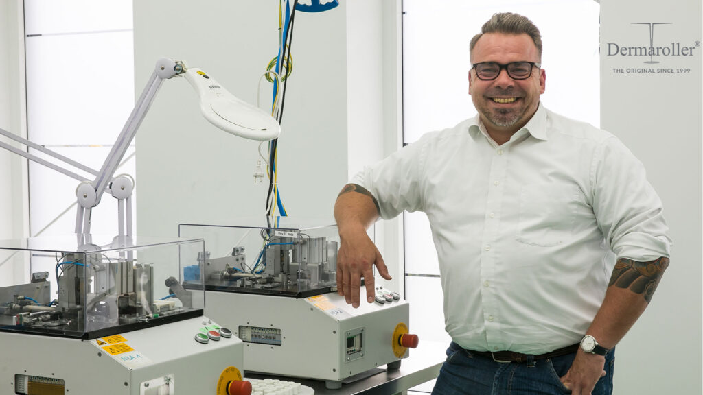 man in glasses stood next to machine smiling