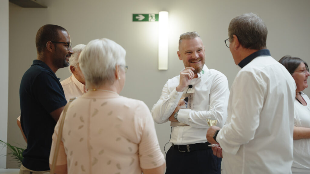 people stood in a circle talking and smiling