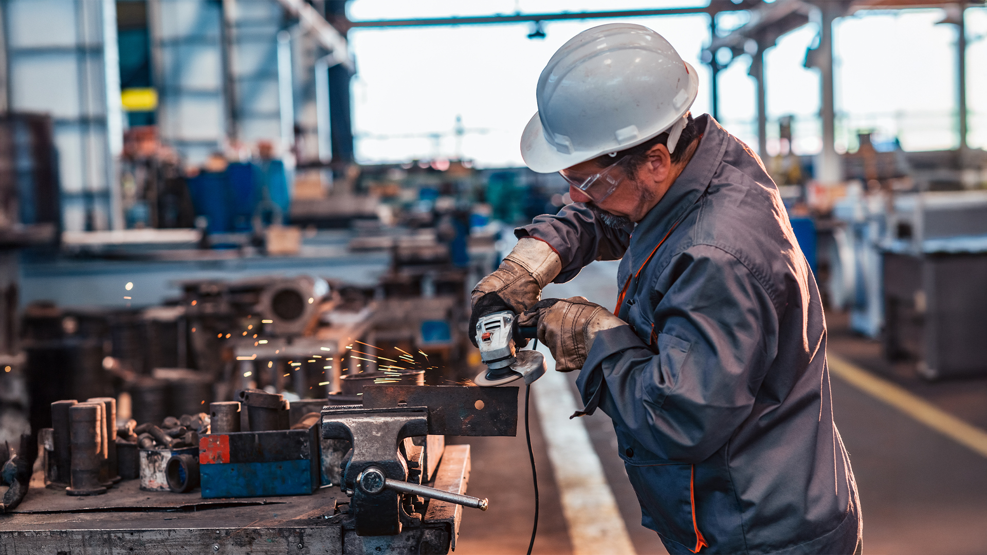 Skilled industrial worker grinding metal part.