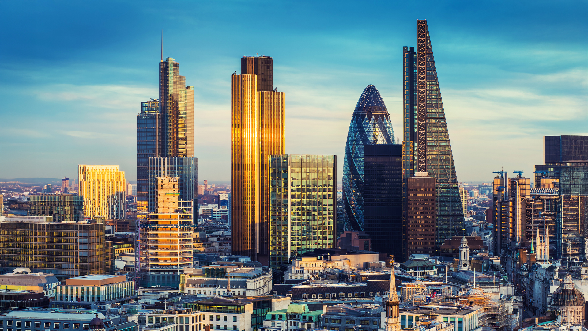 London, United Kingdom - The bank district of central London with famous skyscrapers in golden shine and other landmarks at sunset with blue sky